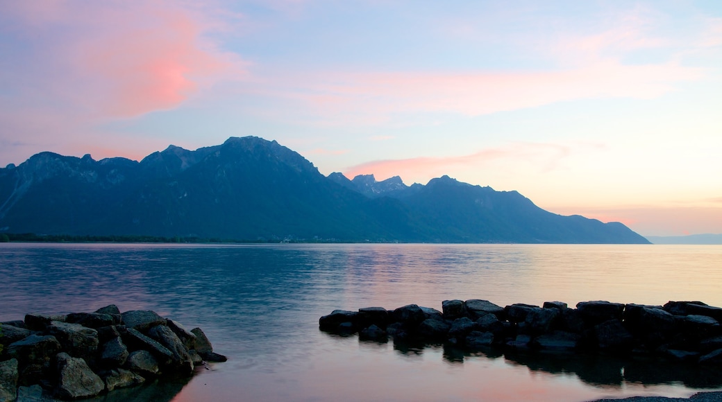 Chateau de Chillon showing mountains, a lake or waterhole and a sunset