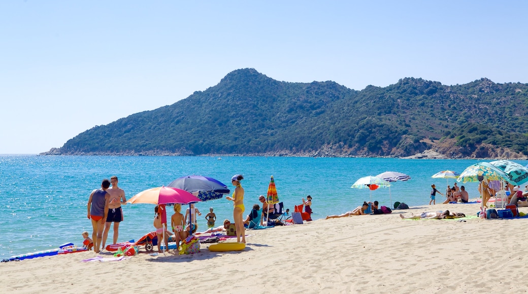 Cala Sinzias som visar en sandstrand såväl som en stor grupp av människor