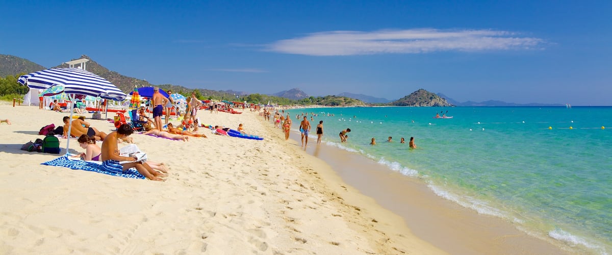 Cala Sinzias featuring a sandy beach as well as a large group of people