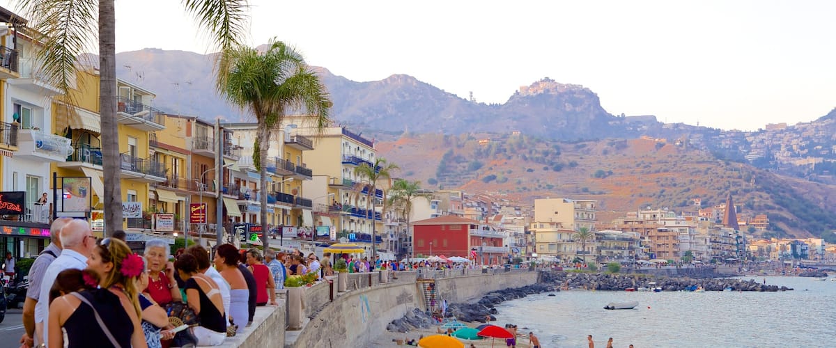 Giardini Naxos que incluye una ciudad costera y una playa de arena y también un gran grupo de personas