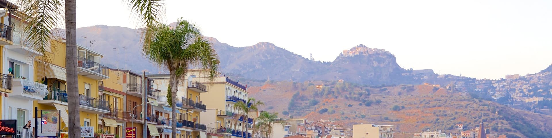 Giardini Naxos which includes a sandy beach and a coastal town as well as a large group of people