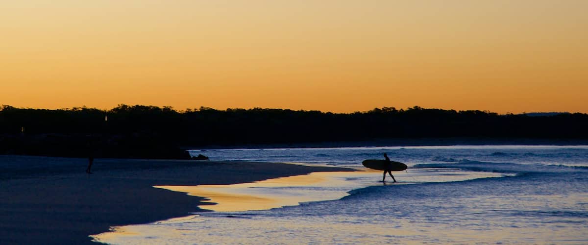 Noosa Beach which includes a beach, a sunset and surfing