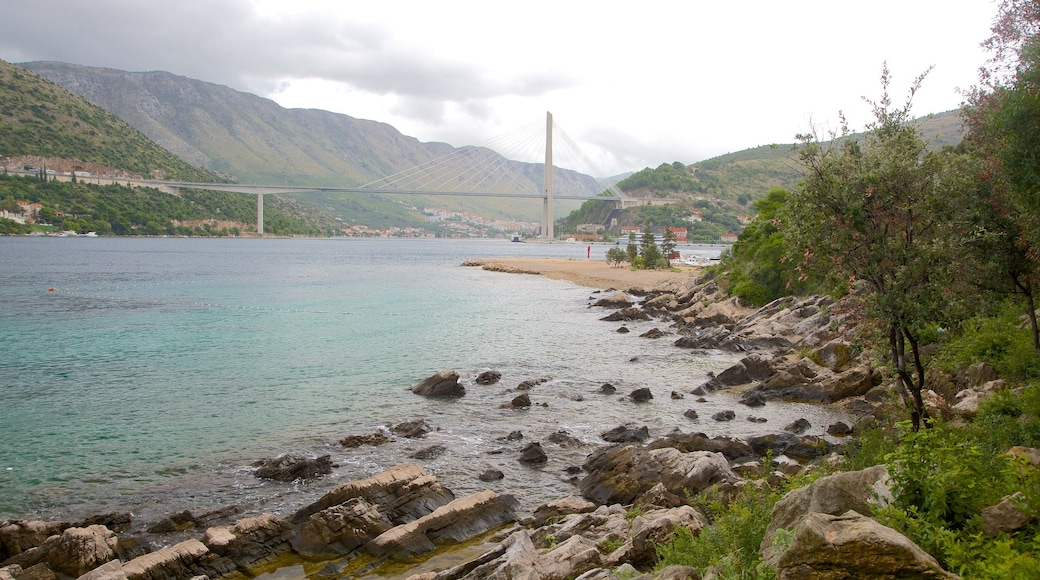 Lapad Beach featuring mountains, a bridge and a bay or harbour