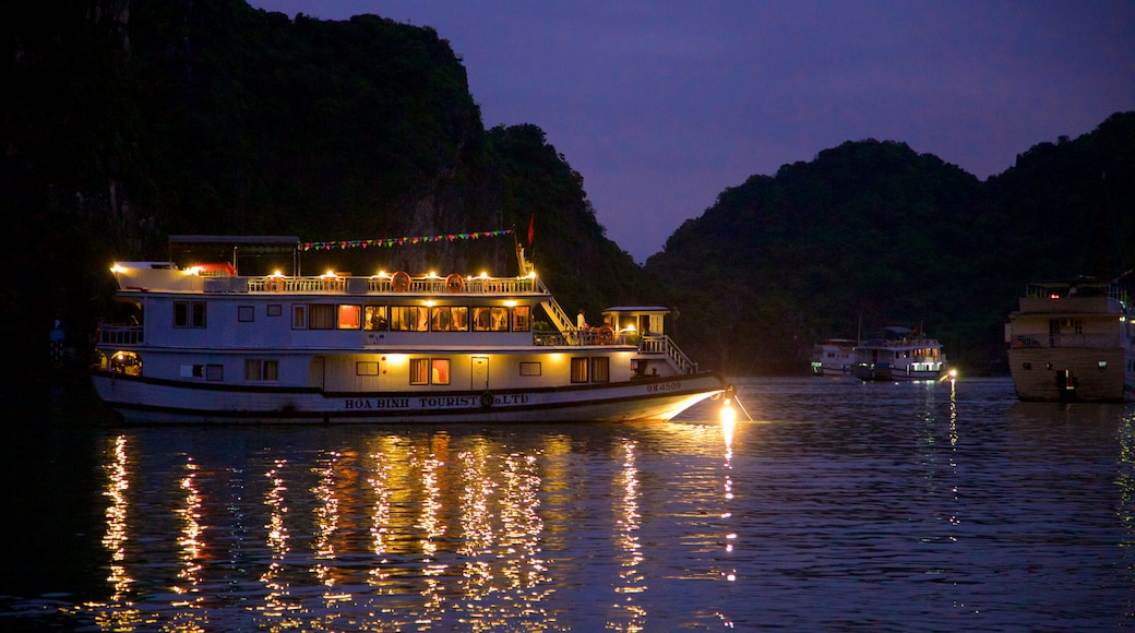 Bahía de Ha Long que incluye botes, montañas y escenas de noche