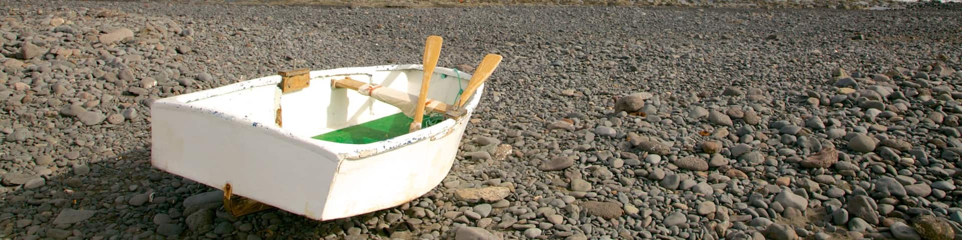 Playa Barca das einen allgemeine KĂŒstenansicht, Bootfahren und Steinstrand