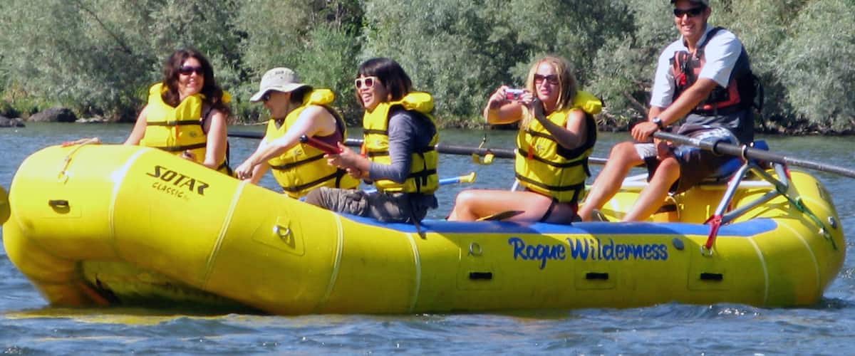 Rogue River featuring a river or creek and rafting as well as a small group of people