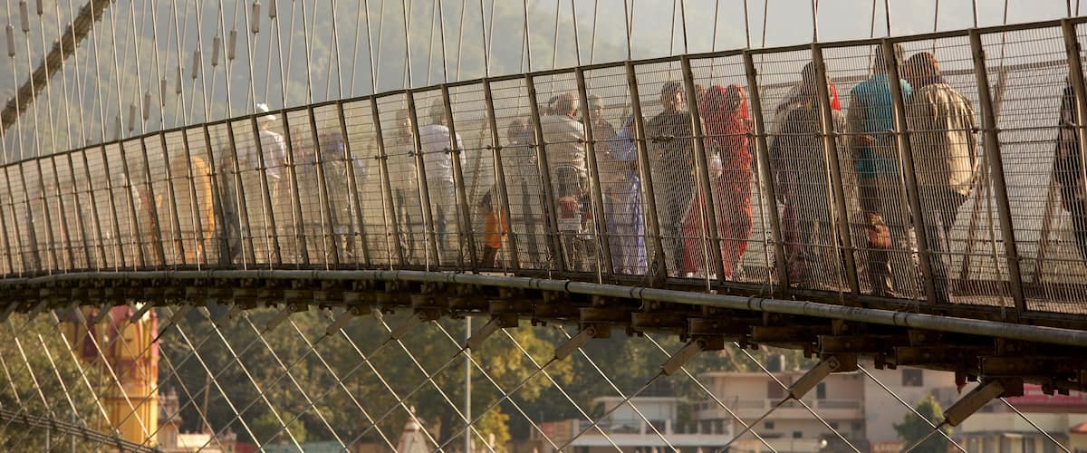 Ram Jhula featuring a suspension bridge or treetop walkway as well as a small group of people