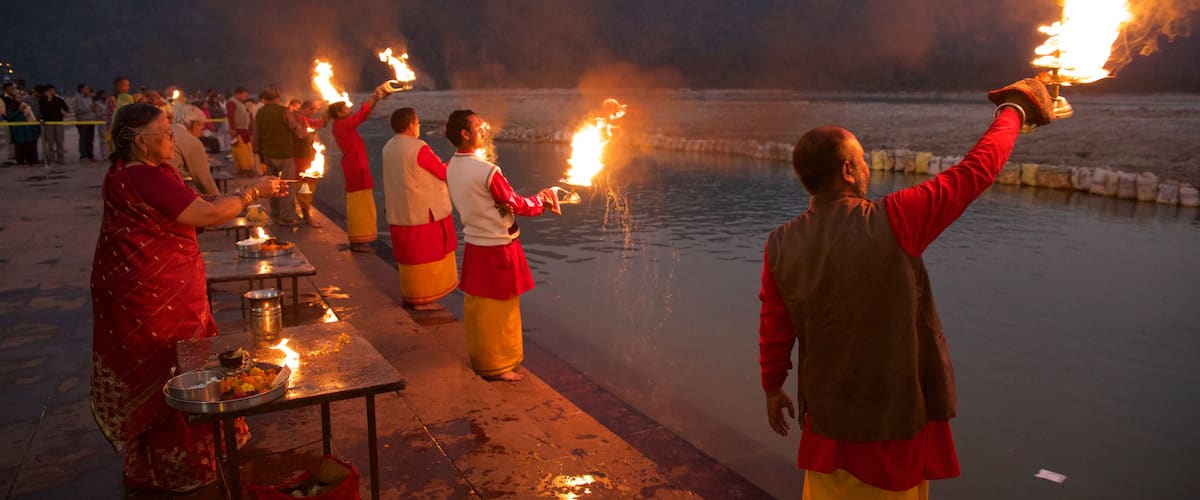 Triveni Ghat mostrando elementos religiosos y una puesta de sol y también un pequeño grupo de personas