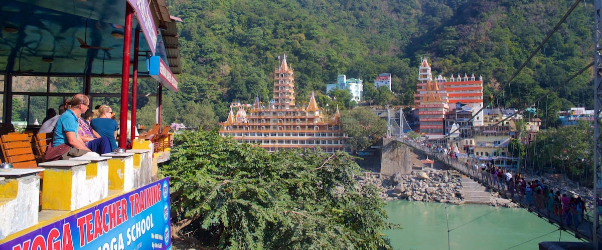 Lakshman Jhula mostrando un río o arroyo, un puente colgante o pasarela en las copas de los árboles y una pequeña ciudad o pueblo
