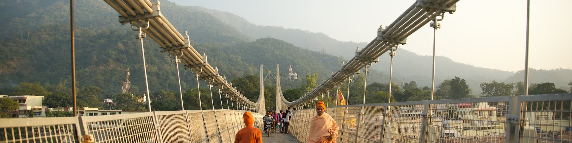 Ram Jhula which includes a suspension bridge or treetop walkway and a small town or village as well as a small group of people