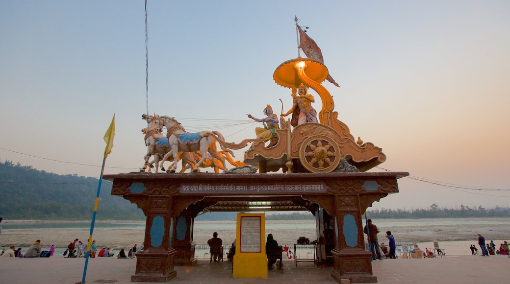 Triveni Ghat caracterizando um rio ou córrego, um pôr do sol e uma estátua ou escultura