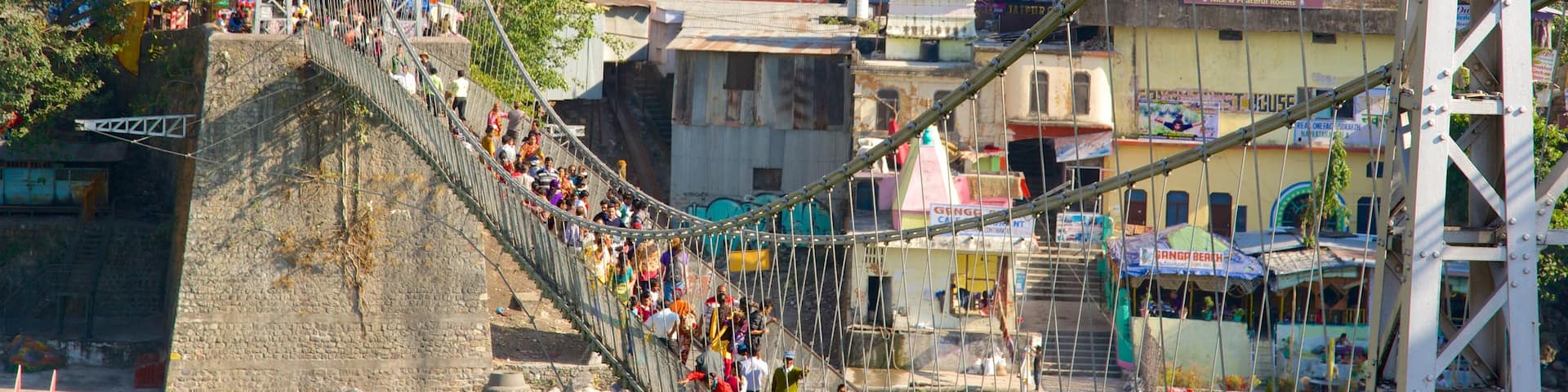 Lakshman Jhula which includes a suspension bridge or treetop walkway and a city as well as a large group of people