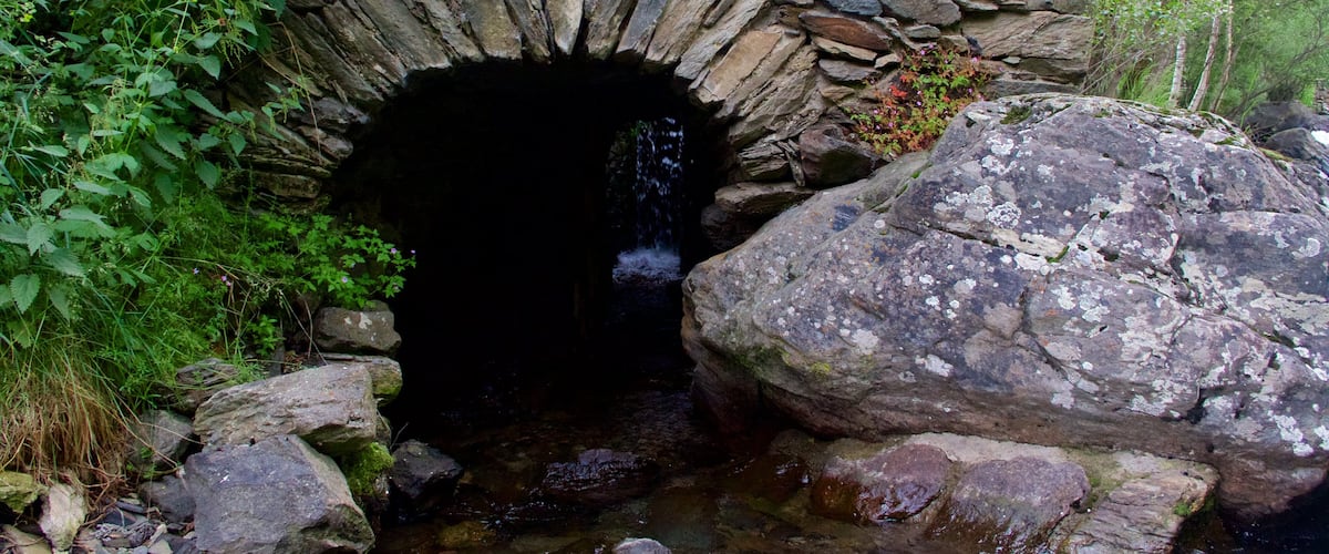 La Cortinada mit einem Fluss oder Bach und Höhlen