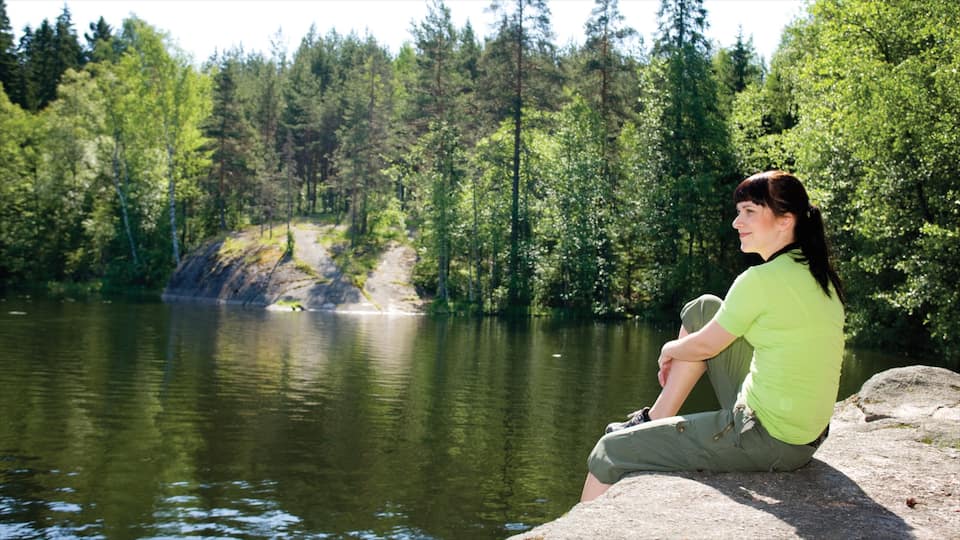 Espoo ofreciendo imágenes de bosques y un lago o espejo de agua y también una mujer