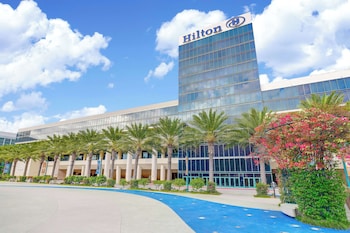 An outdoor event space with tables and chairs, a grassy lawn, and a modern building with large windows in the background.