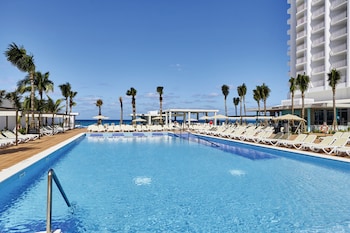 A modern infinity pool with a bar area overlooking the ocean.