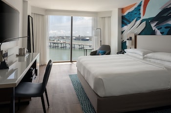 Una sala de estar moderna con un ventanal grande con vistas a un puerto deportivo, un comedor y una zona de estar con vista al agua.