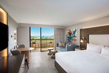 A resort with a large pool, palm trees, and a view of the ocean.
