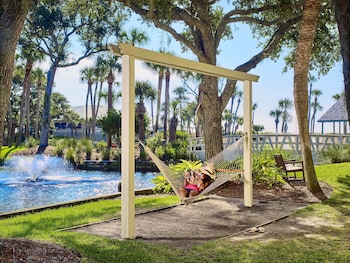 A resort with a large pool, palm trees, and a view of the ocean.