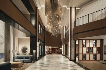 A spacious lobby with a high ceiling, a central staircase, and a modern design.