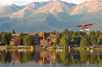 A restaurant with a view of a lake, wooden furniture, and a mounted deer head.
