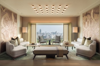 Een moderne lounge met een grote palmboom, comfortabele zitplaatsen en uitzicht op de stad.