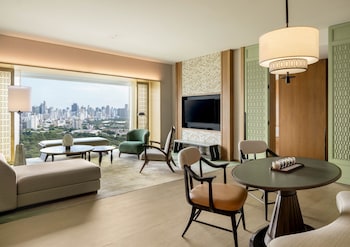 Un salón moderno con una palmera grande, asientos cómodos y vistas de la ciudad.