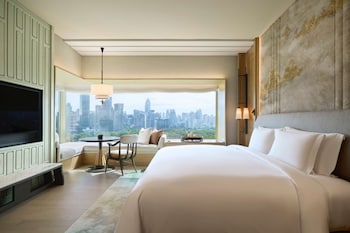 A modern lounge with a large palm tree, comfortable seating, and a view of the cityscape.