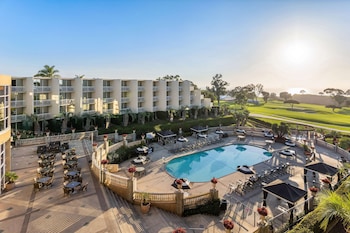 Ein Hotel mit Schwimmbad, Außenbereich und einem Golfplatz im Hintergrund.