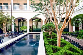 Enter the Peninsula Grill through a charming black iron gate, surrounded by lush gardens and a warm, inviting atmosphere.