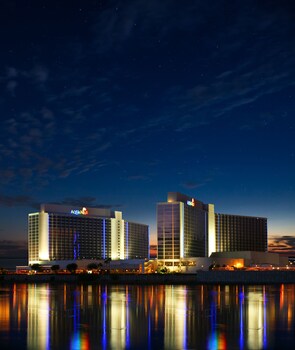 A hotel with a modern design, featuring a prominent 'Aquarius' sign, reflecting in the water.
