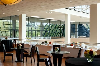 A spacious lobby with a high ceiling, modern lighting, and a staircase leading to an upper level.