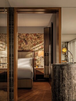 A bathroom with a bathtub filled with red roses, a city view, and a large window.