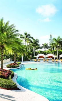 Stunning hotel facade with a central tower and beautifully manicured garden.
