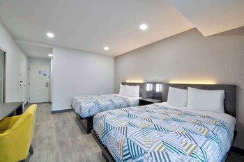 Un hôtel à plusieurs étages avec un parking situé devant, et qui se distingue par un grand panneau en forme de « 6 » sur la façade.