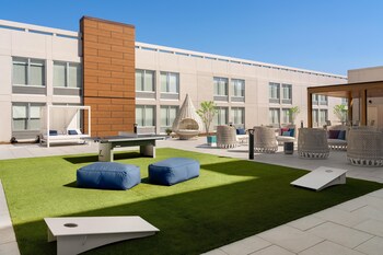 A modern hotel with a swimming pool, lounge areas, and a well-lit exterior.