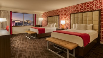 Ein Hotelzimmer mit einem großen Bett, einer Bank, einem Nachttisch und einem Bad mit Badewanne und Waschbecken.