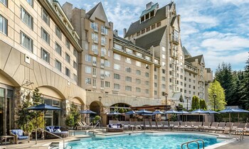 Experience the hotel's unique architecture, featuring a prominent tower and multiple balconies, with a refreshing pool area and comfortable lounge seating.