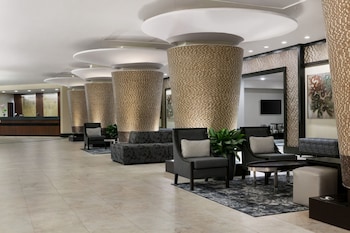 A modern lobby with a reception desk, seating area, and decorative columns.