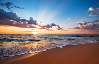 På stranden, hvit sand, strandtelt (mot et tillegg) og solsenger