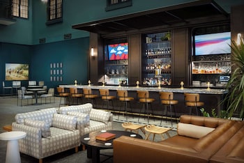 A spacious hotel lobby with multiple seating areas, a bar, and a central fountain.