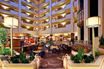 A multi-level hotel lobby with a central seating area, multiple floors, and a variety of amenities including a bar and dining space.