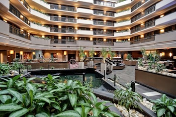 Step into a spacious atrium, surrounded by lush greenery and a grand staircase.