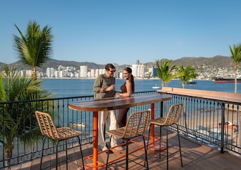 A resort pool with palm trees and a cityscape in the background.