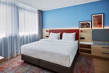 Uma entrada de hotel moderna com uma porta giratória, uma placa com a inscrição "Residence Inn by Marriott" e uma escadaria que leva à entrada.