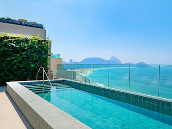 Ein Dachpool mit Infinity-Kante und freiem Blick auf die Küste und ferne Berge.