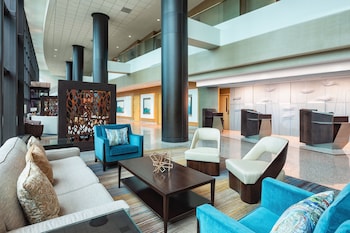 A modern hotel with a reflective glass facade, a prominent "WESTIN" sign, and a landscaped front yard with trees.