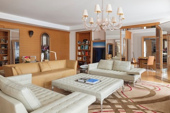 Un balcón con una mesa dispuesta para el desayuno, con vista a una zona residencial con balcones y jardineras.