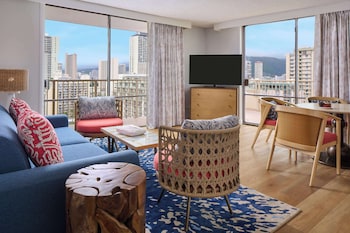 Habitación de hotel con una cama grande, dos mesitas de noche con lámparas, vista al océano y una pared con diseño.