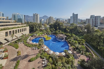 A resort with a pool, palm trees, a gazebo, and outdoor seating.